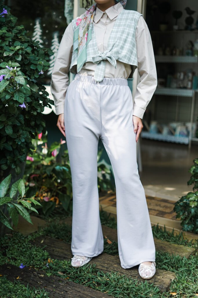 Detail outfit celana kulot abu-abu dengan outer rompi kotak-kotak hijau.