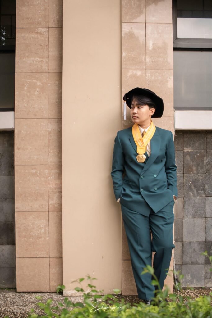 Gaya wisuda pria dengan setelan jas warna teal unik dan kemeja putih, cocok untuk foto kelulusan yang berkesan